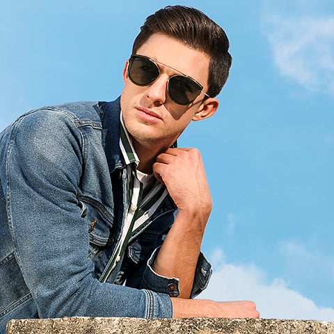 Man wearing aviator style glasses and a denim jacket with a striped shirt