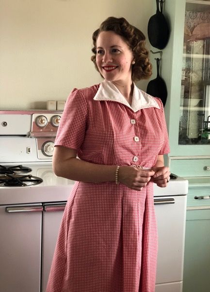 Lady in kitchen wearing house dress 1940's style with white collar and buttoned front