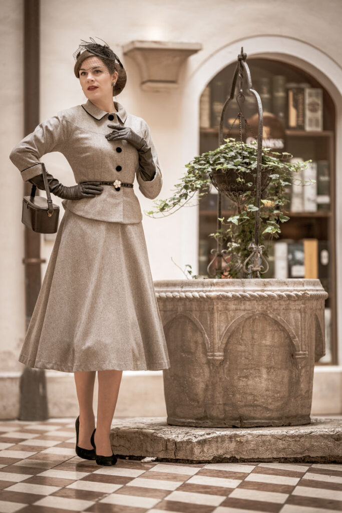 lady in a dress suit with black gloves and a beret fascinator