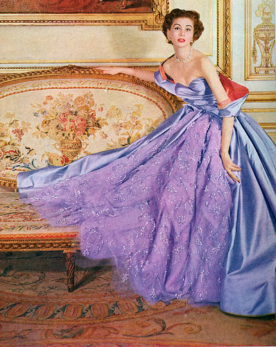 lady standing near a chaise in a sleeveless gown in satin and organza with a matching stole