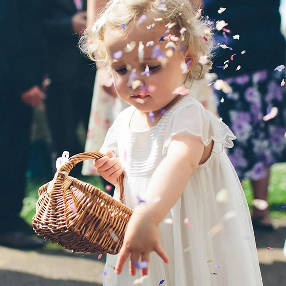 Toddler flower girl throwing petals from a small vintage basket