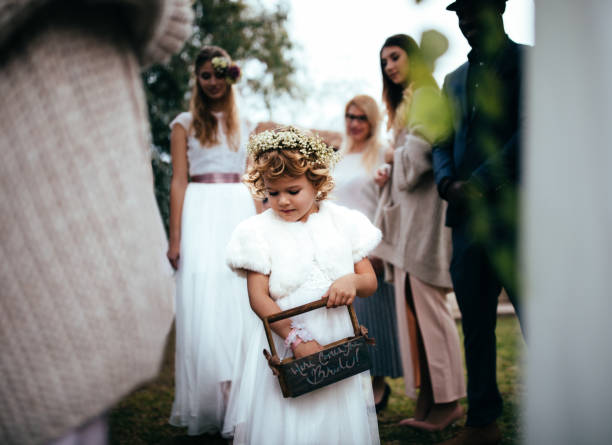 Flower girl with gip hair garland and wearing a fluffy stole throwing flowers from a wooden container