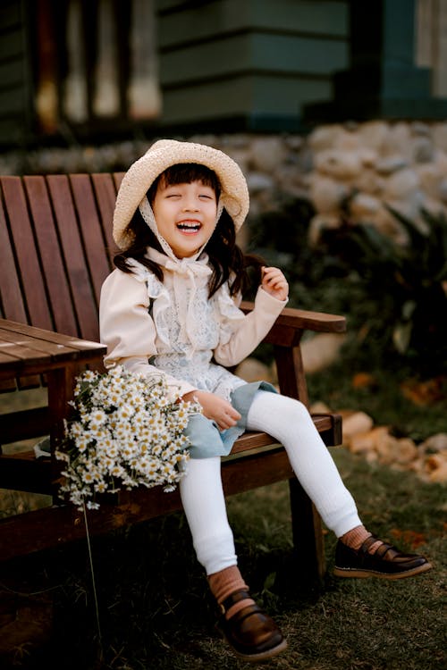 Casual flower girl with a sun hat and ruffled dress in pastel blue shade and white tights