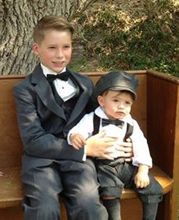 Boy with toddler dressed in a suit and bow tie and toddler in nickerbockers suspenders and newboy hat