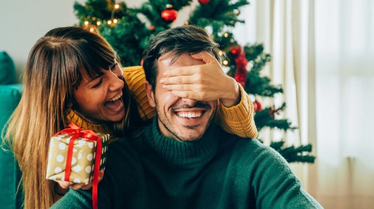 lady and man playing surprise gifts for christmas with tree in the rear