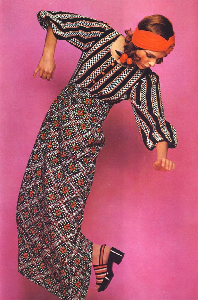 1960's model posing in a mixed pattern kaftan top and skirt with head wrap