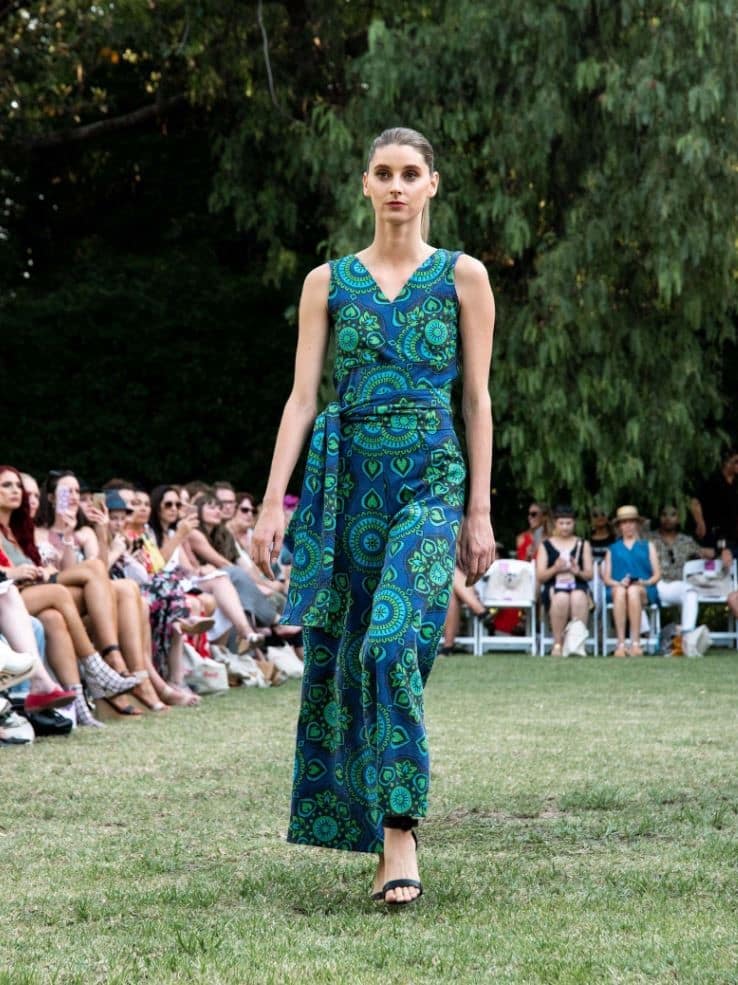 Model wearing a teal patterned eco friendly dress at a fashion parade