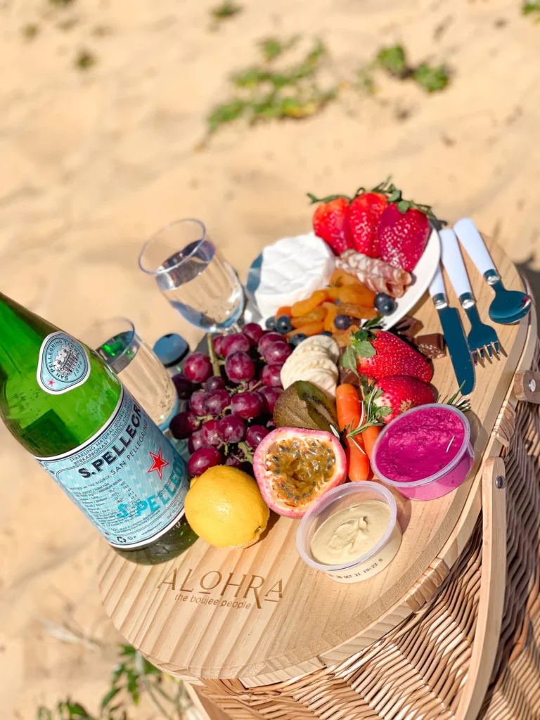 Picnic basket on the beach with fruit dips and spring water bottle