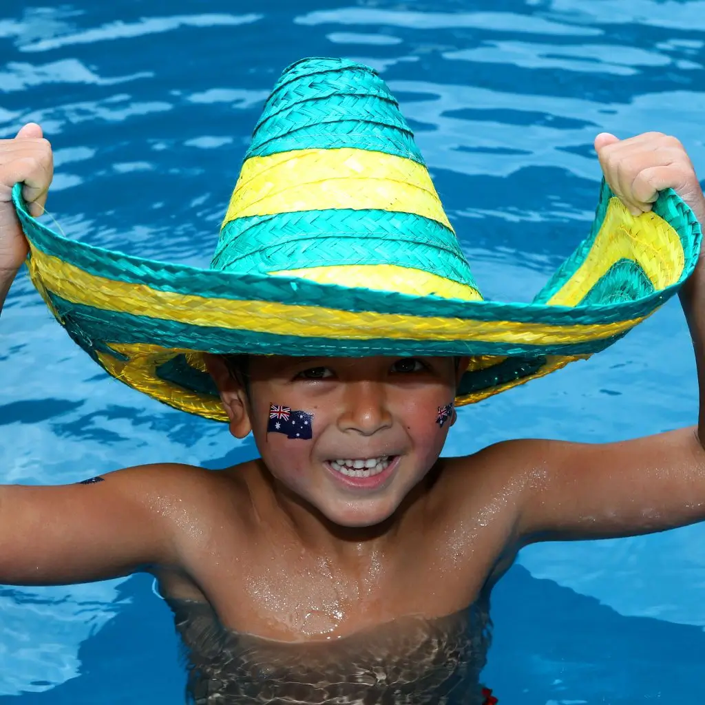 Boy with a green and gold mexican hat in a swimming pool