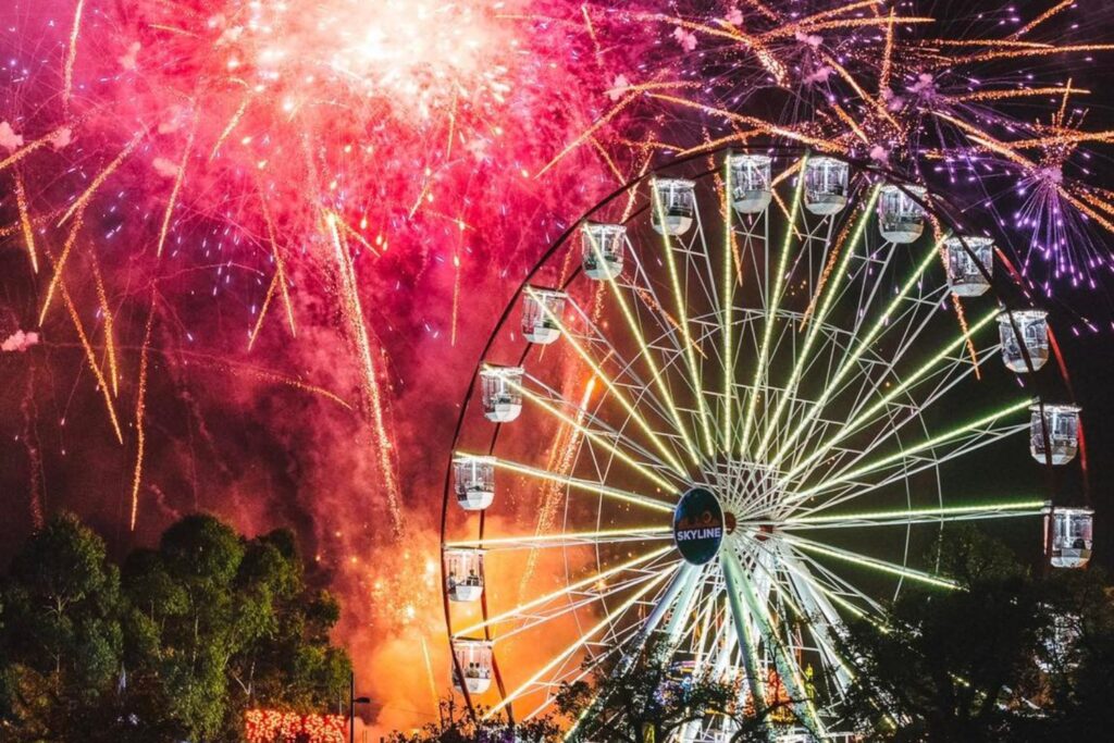 Moomba fireworks during the carnival along the Yarra with rides lit up