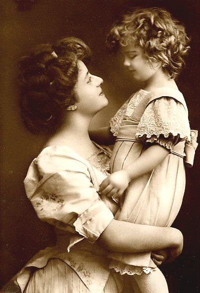 Woman holding daughter - both in frilled dresses
