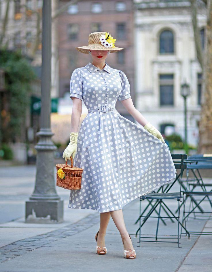 Woman in polka dot dress with hat and small gloves carrying a straw bag