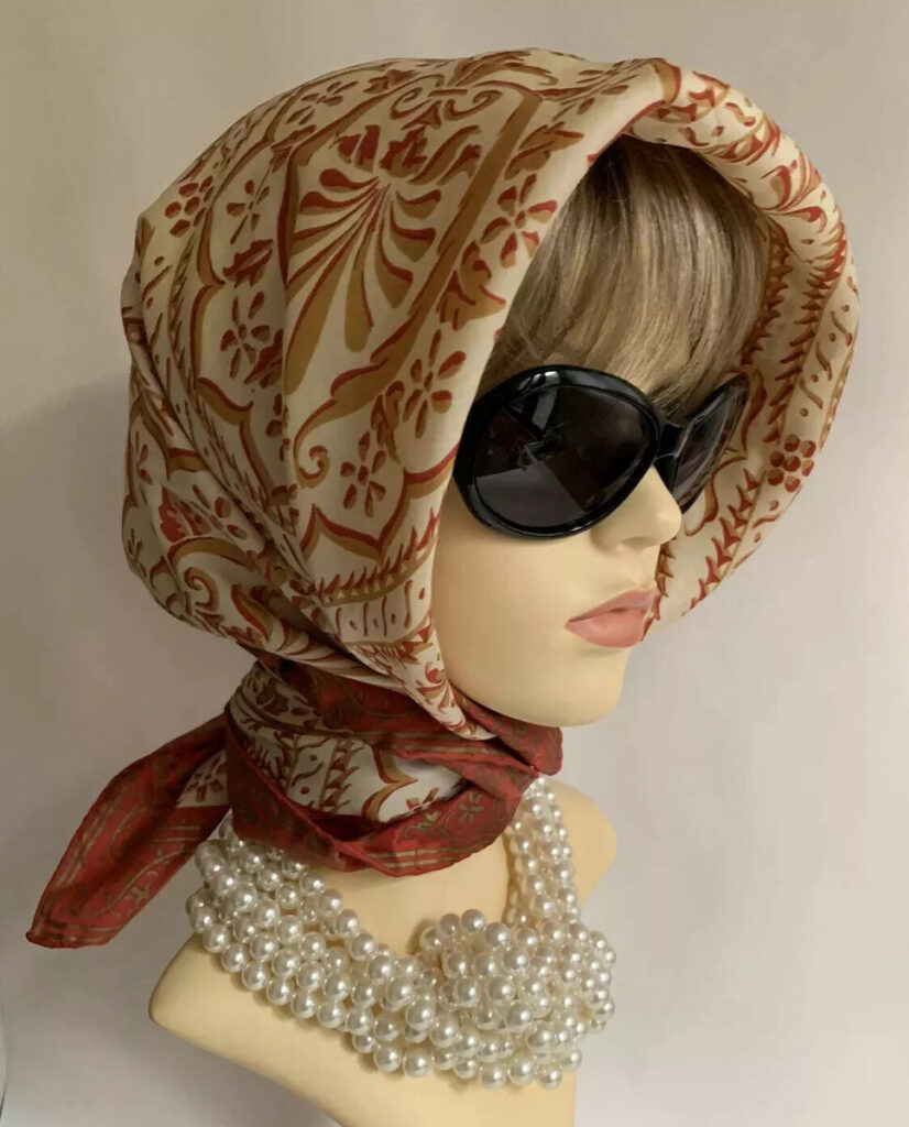 Mannequin bust wearing headscalf pearls and large dark sunglasses - circa 1950's
