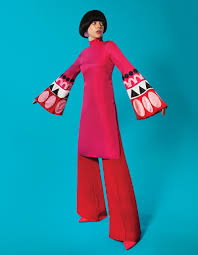 lady wearing kaftan style tunic with bell sleeves and geommetric detail and red wide leg pants