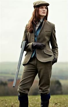 woman wearing a newsboy hat with a rifle and tweed coat and jodpur pants with boots