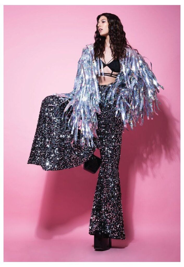 girl modelling dark sparkly baggy pants with platform shoes and a silver tassle shrug jacket