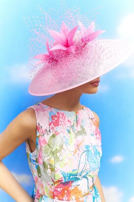 Model in a floral dress with a pink wide brim fascinator hat