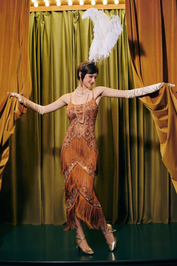 1920's opera dress in burnt orange tones and sequins with large feather headpiece